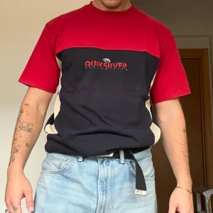 Quiksilver röd och svart t-shirt - Säljer en färgstark t-shirt från Quiksilver i storlek XL. Den sitter som en L. T-shirten har en cool färgblock-design i rött, svart och beige med Quiksilver-logga framtill. Klassisk passform med korta ärmar och rund hals. Perfekt för dig som gillar streetwear och surf vibes.