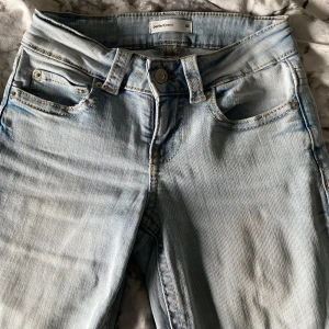 Lågmidjade ljusblå jeans - Ljusblå jeans från Perfect jeans (gina Tricot) med femficksdesign och bakfickor med lock och knapp. Jag har använt dom 1 gång och jeansen är bootcut och sydd i beige/brun tråd 🤍 jag köpte dom för 500kr och skriv vid fler bilder 💋 