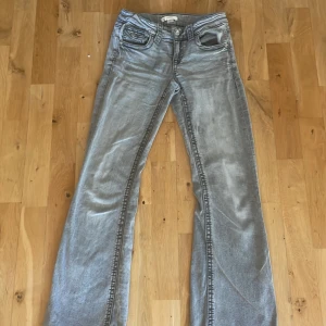 Grå bootcut jeans med slitning - Snygga grå jeans med bootcut-modell och lätt slitning. Klassisk femficksdesign och normal passform. Perfekta för dig som gillar en avslappnad men ändå trendig look.