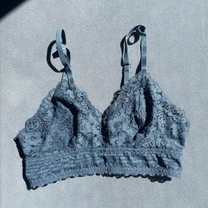 Blå spets bralette H&M - Supersöt blå bralette med blommig spets och justerbara axelband. Toppen har hak- och hyskknäppning bak och bred spetskant nedtill.