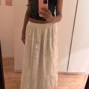 Vit långkjol med spets och snörning - Superfin vit långkjol med broderade spetsdetaljer och snörning i midjan. Kjolen är köpt i en marknad i Spanien och går inte att få tag på.💗Hör av dig vid eventuella frågor och priset kan alltid diskuteras.