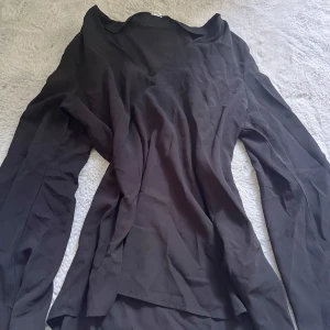 Svart v-ringad blus med långa ärmar - Snygg svart blus med v-ringning och långa ärmar. Tunt och mjukt tyg som faller fint och ger en stilren look. 