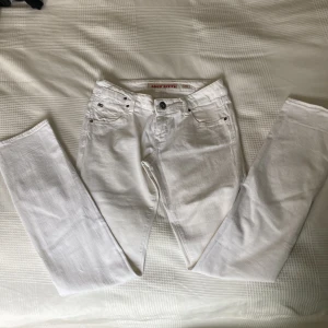 Vita jeans från Miss Sixty, stl 31 - Snygga vita jeans från Miss Sixty i klassisk femficksmodell. Raka ben och normal passform, med metallogo bak på ena fickan. Jeansen har bälteshällor och stängs med knapp och dragkedja. Perfekta för dig som vill ha en fräsch och stilren look.