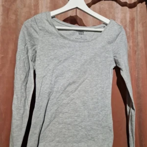 2 långärmade basictröjor från 157 XS - Två långärmade basictröjor från 157 i storlek XS. En i ljusgrått och en i rosa, båda med rund halsringning och smal passform. Grå tröja i bomull, viskos och elastan, rosa i bomull och elastan. Perfekta att styla lager på lager eller till jeans.