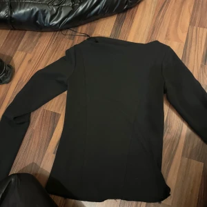 ✨ Elegant svart tröja från Zara – oanvänd! ✨ - Säljer en stilren och elegant svart tröja från Zara, helt oanvänd och i nyskick. Modellen har kortärmade öppningar som ger en modern och luftig känsla – perfekt både till vardags och för festligare tillfällen. Tidlös design som passar året runt.