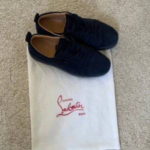 Christian Louboutin - Snygga mörkblå sneakers från Christian Louboutin i mocka med klassisk röd sula och diskret snörning. Skorna har en stilren design.  Säljer dem pågrund av att dem är för små för mig tveka inte på att skriva om du är intresserad :) priset kan diskuteras 