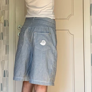 Randiga blå shorts med snörning - Baggy blå- och vitrandiga shorts i 100% bomull köpta i vintagebutik. Inga defekter. Skriv för fler frågor/bilder!