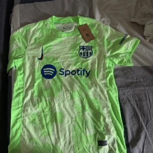 Barcelona Nike fotbollströja neon - Säljer en helt ny Barcelona matchtröja från Nike i neonljus grön färg med blå detaljer.