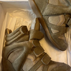 Beige wedge sneakers Isabel Marant - Coola wedge sneakers från Isabel Marant Étoile i beige mocka och skinn. Skorna har högt skaft, breda kardborreband och vadderad plös. Ena skorn har en defekt som enkelt går att fixa men annars är dom i väldigt bra skick! SÄLJER för 3000 eller 2500 vid snabb affär🌸