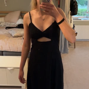 Svart långklänning från BikBok - Svart långklänning från BikBok med smala axelband och snygg cut-out detalj under bysten. Klänningen har en figurnära passform upptill och faller rakt ned. Pris är alltid diskuterbart💗