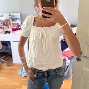 Vit blus med puffärm och rosett från H&M - Supersöt vit blus med puffärmar och smock upptill. Rosett framtill och fyrkantig urringning.