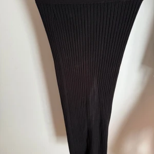 Svart ribbad långkjol från lindex - Svart ribbad långkjol med tight passform och hög midja. Kjolen är stickad och har en klassisk, stilren look som passar perfekt till sneakers eller boots. Enkel att matcha med både t-shirt och stickad tröja. Ej skitig, det är fläckar på spegeln😅🙈