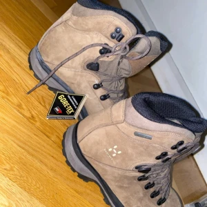  Haglöfs kängor  - Vinter/höst kängor från Haglöfs i beige mocka med svarta detaljer och grov sula. Utrustade med Gore-Tex för vattentäthet och andningsförmåga. Perfekta för utomhusaktiviteter och äventyr.