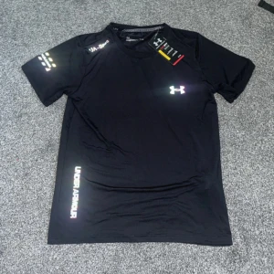 Svart Under Armour compression t-shirt - Svart t-shirt från Under Armour med reflekterande logga på bröstet och sidan. Perfekt för sport. Tillverkad i ett lätt och snabbtorkande material som passar perfekt för träning.