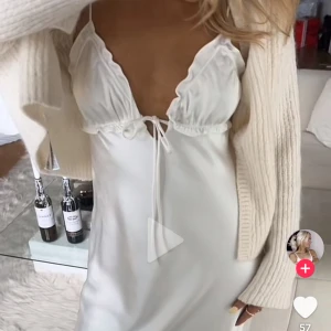 SÖKER Vit ZARAklänning med knyt - Supersöt vit klänning med tunna axelband, omlottdetalj vid bysten och knyt framtill. Klänningen har en mjuk, flowy känsla och är perfekt för varma dagar. Stilren och feminin look med lätt glansigt material.