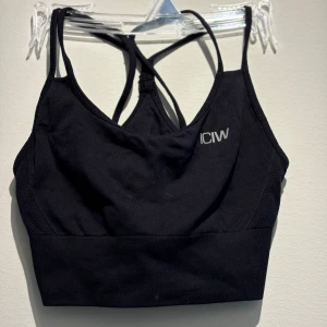 Svart linnetopp från ICANIWILL - Snygg svart linnetopp från ICANIWILL med smala axelband som korsas i ryggen. Toppen är croppad och har en bred resår nedtill för extra stöd. Perfekt för träning eller när du vill ha en sportig look. Materialet är stretchigt och andas bra.