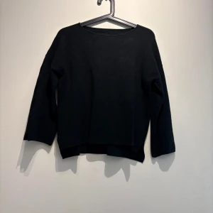 Svart stickad tröja med slitsade ärmar - Svart stickad tröja med lång ärm och coola slitsar på ärmarna. Tröjan har en rak, lite loose passform och är perfekt för dig som gillar minimalistisk stil med en twist. Enkel att matcha och supermjuk mot huden.