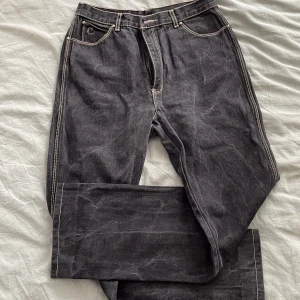 Svarta jeans från Gloria Vanderbilt - Snygga svarta jeans från Gloria Vanderbilt for Murjani med kontrasterande ljusa sömmar och klassisk femficksdesign. Jeansen har broderad svan på myntfickan och raka ben. Perfekta för dig som gillar vintagevibe och coola detaljer.