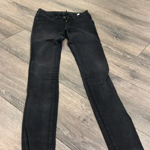 Svarta skinny jeans från Dr Denim - Svarta jeans från Dr Denim med klassisk femficksdesign och smal passform. Jeansen har dragkedja och knapp framtill, bälteshällor och raka bakfickor. Materialet är stretchigt för extra komfort och sitter tight längs benen.