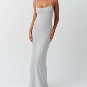 Grå långklänning med smala axelband - Supersnygg grå långklänning med smala axelband och figurnära passform. Klänningen är ärmlös och har en enkel, stilren design som passar perfekt för en clean och modern look. Mjuk och stretchig bomullskänsla för maximal komfort.