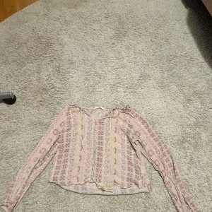 Mönstrad blus från Pink Rose - Säljer en söt blus från Pink Rose med ett ljust mönster i rosa och beige. Blusen har långa ärmar och knappar framtill. Skitsnygg att ha på vardag och fester❤️❤️pris kan diskuteras 