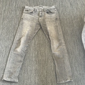 Grå jeans från Polo Ralph Lauren - Snygga grå jeans från Polo Ralph Lauren i modellen The Sullivan Slim. De har en klassisk femficksdesign och en slim passform som ger en stilren look. Perfekta för en avslappnad men ändå stilfull outfit.