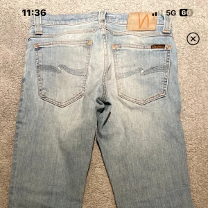 Ljusblå jeans från Nudie Jeans - Snygga ljusblå jeans från Nudie Jeans med klassisk femficksdesign och orange sömmar. Jeansen har en bekväm passform och är perfekta för en avslappnad stil. Märkeslogga på baksidan.
