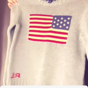 Grå stickad tröja med amerikansk flagga - Säljer min favorit tröja nu kommer ai beskrivningen. en grå stickad tröja från Ralph Lauren med en stor amerikansk flagga på framsidan. Tröjan har långa ärmar och en rund halsringning. Perfekt för kyliga dagar!