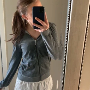 Grå hoodie med dragkedja - Säljer en stilren grå hoodie med dragkedja framtill. Tröjan har långa ärmar och en bekväm passform, perfekt för vardagsbruk. Den har också praktiska fickor framtill. Perfekt för en avslappnad look!