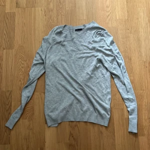 Grå tröja från 157 - Säljer en stilren grå tröja från 157. Den är långärmad och har en klassisk rund halsringning. Perfekt för en avslappnad look. Passar bra till jeans eller chinos.