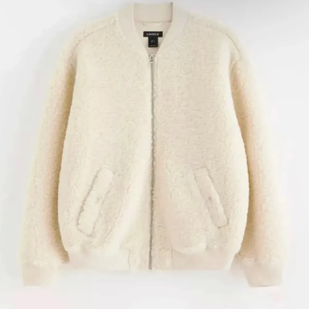 Mysig beige teddyjacka från Lindex med dragkedja framtill. Jackan har långa ärmar och ribbade muddar vid ärmslut och nederkant. Perfekt för kyliga dagar när du vill vara både varm och stilren. ny pris 699. Takit.
