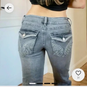 Grå jeans med broderade fickor - KOLLA min profil för fler liknande jeans! Snygga grå jeans med unika broderade detaljer på bakfickorna. De har en klassisk femficksdesign och knäppning fram. Perfekta för en stilren look. Low waist bootcut jeans från Gina Young! Ursnygga och trendiga jeans som är slutsålda. Strl 170 vilket jag tycker motsvarar liten m men har stretch. OBS! Dessa jeans har ett litet hål på  rumpan som knappt syns,  enkelt går att laga! Kom privat för bilder 🥰
