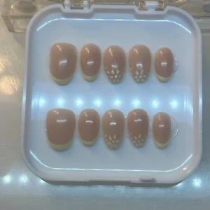 Beige och gula lösnaglar med blommönster - Snygga lösnaglar i beige med gul fransk manikyr och blommönster. Perfekta för att ge dina naglar en unik och stilren look. Kommer i en praktisk förpackning.pressons 