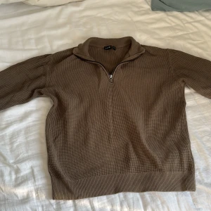 Brun stickad tröja från LMTD - Säljer en brun stickad tröja från LMTD med dragkedja vid halsen. Tröjan har långa ärmar och en ribbad struktur som ger en stilren look. Perfekt för kyligare dagar.