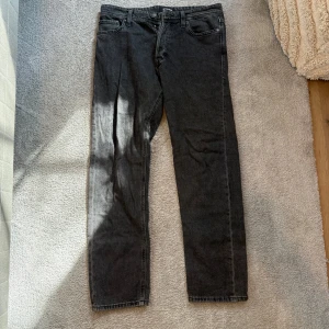 Grå jeansbyxor - Snygga grå jeansbyxor med en klassisk straight passform. De har en midwaist design och är perfekta för en avslappnad stil. Byxorna stängs med knappar.