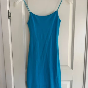 Blå ärmlös klänning - Snygg blå klänning med smala axelband och enkel design. Perfekt för varma dagar eller en kväll ute. Klänningen har en smickrande passform och är lätt att styla med olika accessoarer.