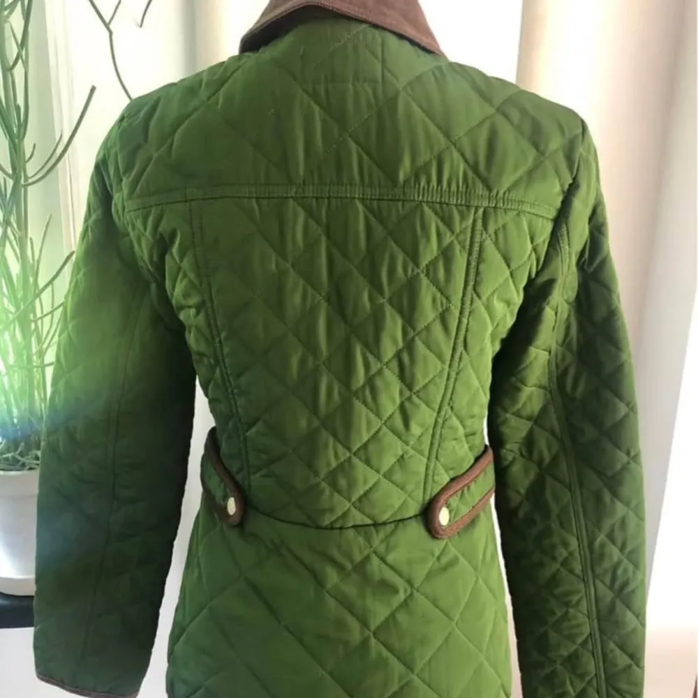 Snygg grön quiltad jacka från Stockh LM med bruna detaljer och krage. Jackan har knappar framtill och praktiska fickor med knäppning. Perfekt för höst och vår med sin stilrena design och bekväma passform.. Takit.