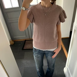 Kortärmad stickad tröja med volanger  - Rosa/lila stickad topp från Lindex i storlek M, skulle säga att den även passar S. Fint skick. Använd gärna köp nu!