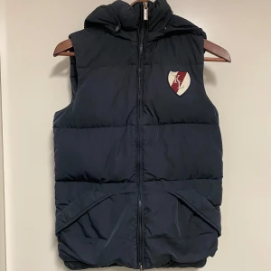 Marinblå dunväst från Kingsland - Säljer en marinblå dunväst från Kingsland Classic Collection. Superfin men något urtvättad färg. Storlek 3Xs men passar som Xs. Originalpris ca 1999 kr. 