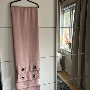 Rosa gardin med öljetter - Säljer en stilren rosa gardin med stora silverfärgade öljetter för enkel upphängning. Gardinen har en mjuk och elegant look som passar perfekt för att ge rummet en varm känsla. Perfekt för att skapa en mysig atmosfär i hemmet.