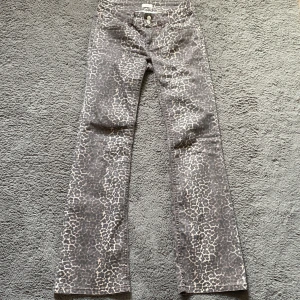 Leopardmönstrade byxor från Nelly - Snygga leopardmönstrade byxor från Nelly med bootcut-stil. Byxorna har en hög/låg midja och är perfekta för att ge en trendig touch till din outfit. 