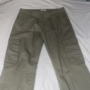 Olivgröna cargobyxor från Perfect Jeans - Snygga olivgröna cargobyxor från Perfect Jeans med praktiska fickor på sidorna. Byxorna har en avslappnad passform och är perfekta för en casual look. De är tillverkade i ett slitstarkt material som passar bra för vardagsbruk.