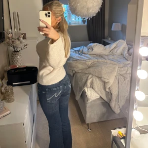 Blå bootcut jeans - Trendiga jeans från Nelly, enbart använda en gång. Snygga blå bootcut jeans med låg midja och klassisk femficksdesign. Jeansen har en stilren look med en knapp och dragkedja framtill. Perfekta för en avslappnad stil.