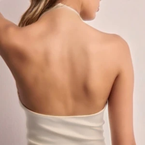 Halterneck linne - Säljer ett stilrent beige halterneck linne med draperad framsida. Perfekt för en somrig look. Linnet har tunna band som knyts i nacken. Jag vet inte storleken men det känns som ett S