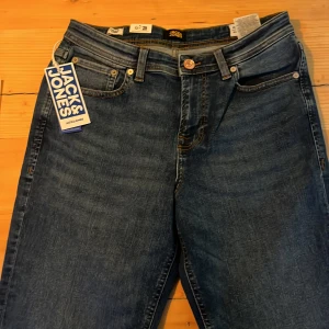 Blå jeans från Jack & Jones - Snygga blå jeans från Jack & Jones i modellen Regular Clark. De har en klassisk femficksdesign med knapp och dragkedja framtill. Perfekta för en avslappnad stil.