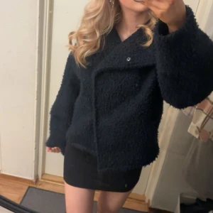 Marinblå teddyjacka - Mysig marinblå teddyjacka med en oversized passform. Jackan har långa ärmar och en stilren design utan synliga detaljer som dragkedjor eller knappar. Perfekt för kyligare dagar när du vill hålla dig varm och bekväm. Även perfekt nu till våren