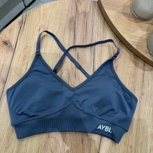 Grå sporttopp från AYBL - Säljer en grå sporttopp från AYBL med korsade axelband som går att justera. Toppen är från kollektionen ”ADAPT” och är aldrig använd!