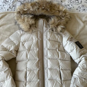 beige dunjacka med pälsdetaljer från bubbleroom - Snygg beige/vit dunjacka från Chiara Forth med en fluffig pälsfodrad huva. Använd vid skidåkning enbart en vecka! Passar superbra till tidig vår också. Sminkavtryck på insidan, men det går att få bort allt i ordentlig tvätt, reducerar priset en aning för det, men annars nyskick! Köpt för 999kr🧥❄️