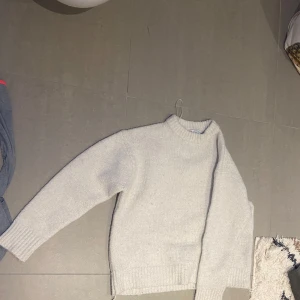 Vit stickad tröja från Zara - Säljer en mysig vit stickad tröja från Zara. Tröjan har en klassisk design med långa ärmar och ribbstickade muddar vid ärmslut och nederkant. Perfekt för kyliga dagar!