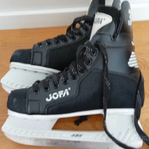 Svarta skridskor från Jofa - Säljer ett par klassiska svarta skridskor från Jofa. De har en robust design med snörning och vit sula. Perfekta för vinterns isäventyr.